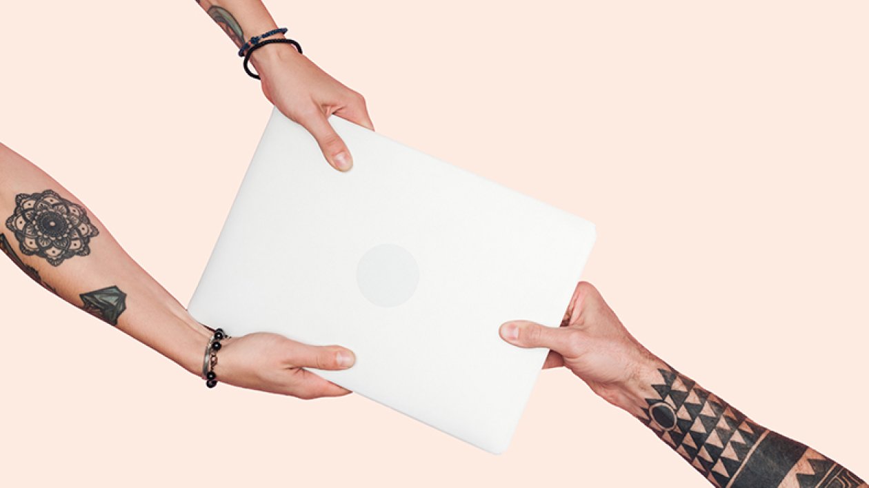 Tattooed people pulling laptop on a light beige background.