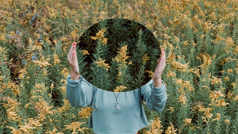 A girl holding a round mirror in front of her face