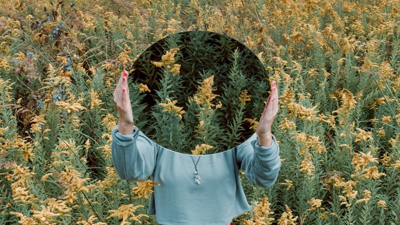 A girl holding a round mirror in front of her face 